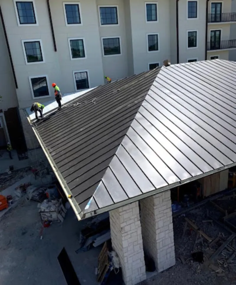 Crew installing standing seam metal roof panels on a commercial project in Durham